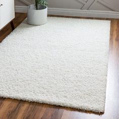 a white rug with a potted plant on the floor