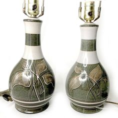 two vases that are sitting next to each other on a white surface with one light turned on