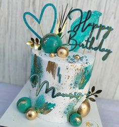 a white and blue birthday cake with gold decorations