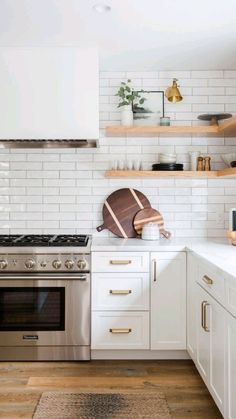 a kitchen with white cabinets and gold trim on the stove top, shelves above it