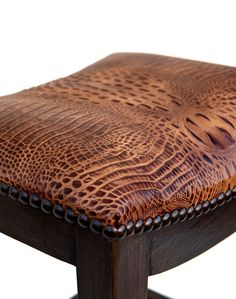 a close up of a wooden stool with alligator skin on the seat and wood frame