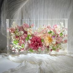 a vase filled with lots of flowers on top of a white bed cover covered in sheets