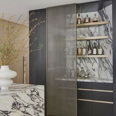 an elegant kitchen with marble counter tops and black cabinetry, along with white vases