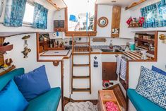 the interior of a small boat with blue couches and wooden ladders on the wall