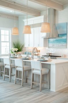 a large kitchen with white cabinets and wooden flooring next to a dining room table