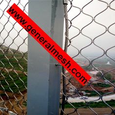 a red tape is taped to the side of a chain link fence with an area in the background