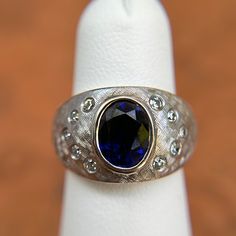 Estate/ vintage 14KT white gold oval-cut, synthetic, dark blue sapphire + gypsey-set diamond domed ring. Size 4.75 Can be resized for an additional fee Weight: 7.30 grams (10) natural, round diamonds SI/1, G Color diamonds Gypsy-set diamonds Sapphire: synthetic sapphire measures approx.: 8mm x 6mm Oval-cut, Dark Navy blue, Faceted sapphire Brushed Matte Finish Excellent estate condition Collectible Oval Sapphire Ring With Diamonds, Oval Sapphire Ring With Diamonds For Collectors, Modern Oval Sapphire Ring With Diamond, Collectible Oval Sapphire Ring With Center Stone, Modern Oval Sapphire Ring For Anniversary, Unique Oval Sapphire Ring With Center Stone, Modern Oval Sapphire Anniversary Ring, Collectible Oval Sapphire Diamond Ring, Modern Oval Sapphire Ring With Accent Stones