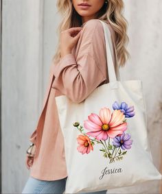 a woman carrying a tote bag with flowers painted on it