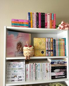 a bookshelf filled with lots of books next to a vase and stuffed animal