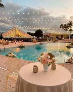 a table with flowers on it next to a pool