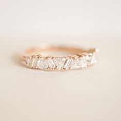 a gold ring with five baguetts of diamonds on the side, sitting on a white surface