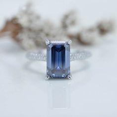 a blue and white diamond ring sitting on top of a table