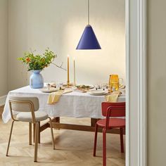 a dining room table with two chairs and a blue vase on the top of it