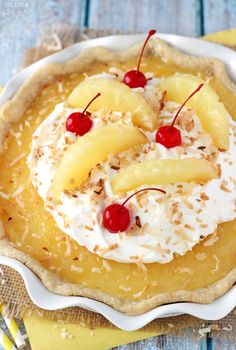 a pie with pineapples and whipped cream on top, topped with cherries