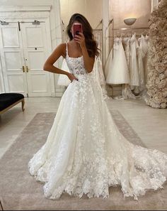 a woman taking a selfie in her wedding dress while looking at her cell phone