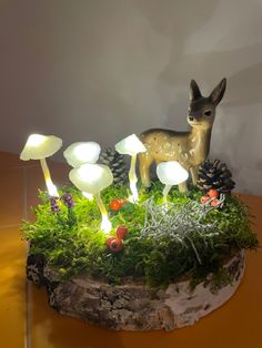 a small deer figurine sitting on top of a moss covered table next to mushrooms