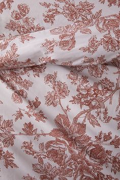 an orange and white floral print fabric with red flowers on the bottom half of it