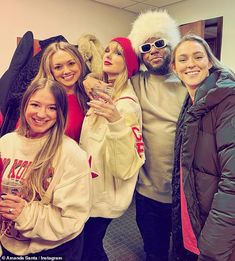 a group of people standing next to each other wearing winter clothing and holding wine glasses