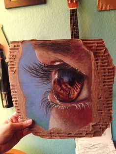 someone is holding up a drawing of an eye with the image of a person's face on it