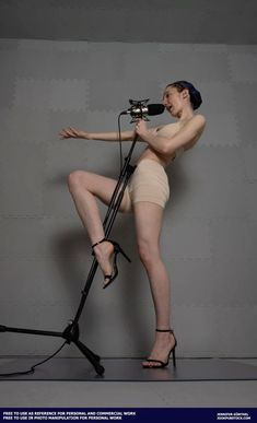 a woman is standing on a tripod with a microphone in her hand and wearing high heels