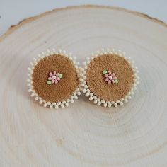 two small white and pink flowers are placed on top of a piece of brown wood