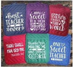 four pot holders with sayings on them in different colors and font styles, sitting on top of a wooden surface