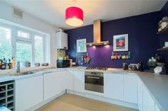 a kitchen with white cabinets and purple walls