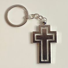 a metal cross keychain on a white surface