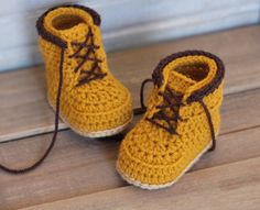 a pair of yellow crocheted shoes sitting on top of a wooden floor next to a wall