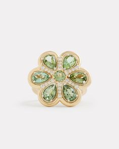 a gold ring with green and white stones on it's center, surrounded by diamonds