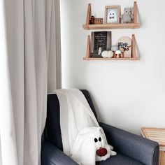 a living room with two shelves on the wall and a stuffed animal in the corner