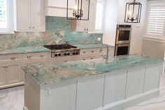 a large kitchen with marble counter tops and white cabinets, along with an island in the middle