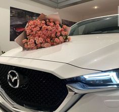 a bouquet of roses is placed on the hood of a white car in a showroom