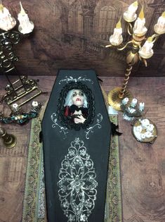 a table topped with a black cloth covered casket next to candles and other decor on top of a wooden floor