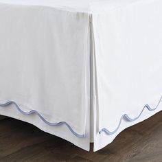 a bed with white sheets and blue trim on the bottom edge is shown in this image