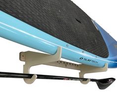 a blue surfboard is attached to the side of a board rack with two paddles