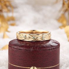 a gold wedding band sitting on top of a wooden box with snow flakes in the background