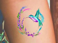 a tattoo on the side of a woman's thigh with a hummingbird and lavenders