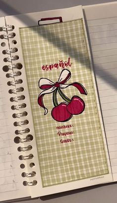 an open spiral notebook with two cherries on it