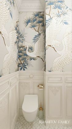 a white toilet sitting inside of a bathroom next to a wallpaper covered in birds