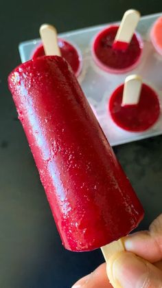 a hand holding a popsicle that is covered in red liquid and marshmallows