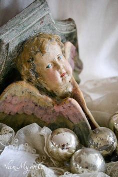 an angel statue sitting on top of a bed next to some christmas balls and other decorations