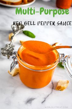 a glass jar filled with red bell pepper sauce on top of a white marble counter