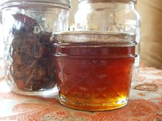 three jars filled with different types of food on a tableclothed surface, next to each other