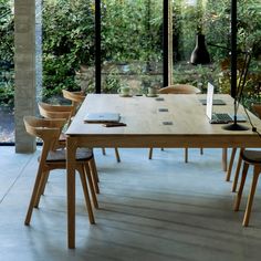 a wooden table with several chairs around it and a laptop on top of the table