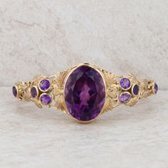 This ladies 10k yellow gold bangle features one large oval amethyst that measures 23x17mm. It also features four bezel set 4mm amethysts on either side as well as gold floral details throughout the bangle. The bangle is 25mm at the widest part, by the oval amethyst and the back of the bangle shows filigree and milgrain details. The bangle measures 7" and the push clasp has a figure eight safety catch. Condition: Pre-Owned *All items are thoroughly inspected for quality assurance purposes Amethyst Bangle, Yellow Gold Bangle, Fine Jewelry Bracelets, Gold Bangle, Gold Floral, Heel Boots, Quality Assurance, Gold Bangles, Bezel Setting