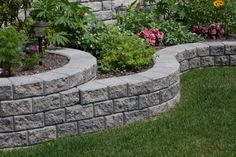 a stone wall in the middle of a flower garden