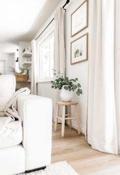 a living room with white furniture and pictures on the wall