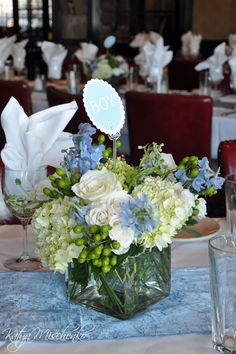 a vase filled with white and blue flowers sitting on top of a dining room table