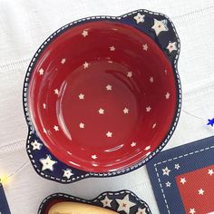 a red bowl with white stars on it next to a hot dog bun and an american flag place mat